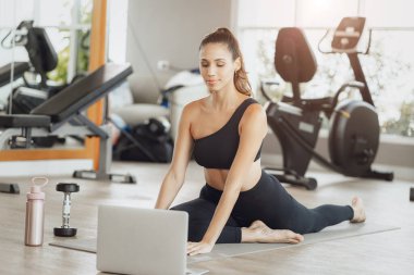 Çevrimiçi Sağlık Eğitimi. Genç Fit Kadın Spor Kulübü 'nde egzersiz yapıyor, Dizüstü bilgisayarda video dersi izliyor.