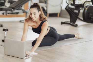 Çevrimiçi Sağlık Eğitimi. Genç Fit Kadın Spor Kulübü 'nde egzersiz yapıyor, Dizüstü bilgisayarda video dersi izliyor.