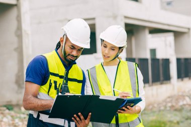 İnşaat mühendisi, mühendis ekip çalışanı ve kadınlar inşaat alanında ev yapımı projeleriyle birlikte çalışıyorlar.