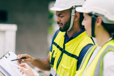 İnşaat mühendisi, mühendis ekip çalışanı ve kadınlar inşaat alanında ev yapımı projeleriyle birlikte çalışıyorlar.