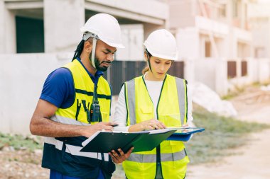 İnşaat mühendisi, mühendis ekip çalışanı ve kadınlar inşaat alanında ev yapımı projeleriyle birlikte çalışıyorlar.