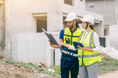 İnşaat mühendisi, mühendis ekip çalışanı ve kadınlar inşaat alanında ev yapımı projeleriyle birlikte çalışıyorlar.