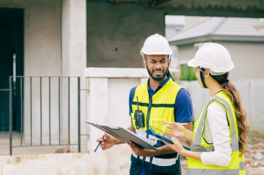 İnşaat mühendisi, mühendis ekip çalışanı ve kadınlar inşaat alanında ev yapımı projeleriyle birlikte çalışıyorlar.
