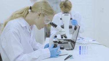 Bilim laboratuarında çalışan bilim adamı doktor ekibi, tıp araştırmacısı ekip çalışması farmasötik laboratuarında bilgisayar teknolojisi ekipmanları ve mikroskop ile araştırma yapıyor.