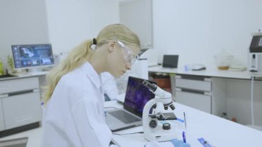 Bilim laboratuarında çalışan bilim adamı doktor ekibi, tıp araştırmacısı ekip çalışması farmasötik laboratuarında bilgisayar teknolojisi ekipmanları ve mikroskop ile araştırma yapıyor.