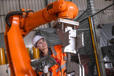 Teknisyen mühendis kadın test kontrol kontrol kontrol robot kol kurulumu fabrikada. İşçi denetimi denetleyici aygıtla robotu ayarlıyor.