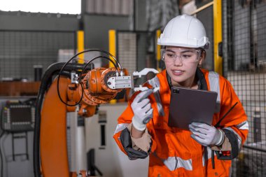 Teknisyen mühendis kadın test kontrol kontrol kontrol robot kol kurulumu fabrikada. İşçi denetimi, robotu tablet aygıtıyla ayarlıyor.