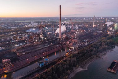 Şafak vakti Kuzey Ren-Vestfalya 'daki Metalurji Fabrikası' nda. Çelik fabrikasının yanı sıra, bir kola fabrikası, fırınlar, bir elektrik santrali ve bir sinter fabrikası işletiyor..