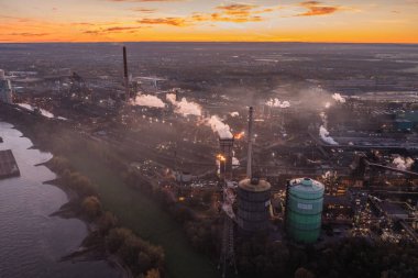 Şafak vakti Kuzey Ren-Vestfalya 'daki Metalurji Fabrikası' nda. Çelik fabrikasının yanı sıra, bir kola fabrikası, fırınlar, bir elektrik santrali ve bir sinter fabrikası işletiyor..