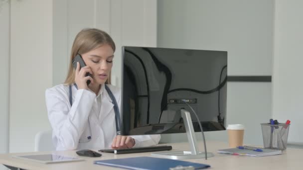 Lady Doctor Μιλώντας Στο Τηλέφωνο Ενώ Εργάζονται Επιτραπέζιο Υπολογιστή — Αρχείο Βίντεο