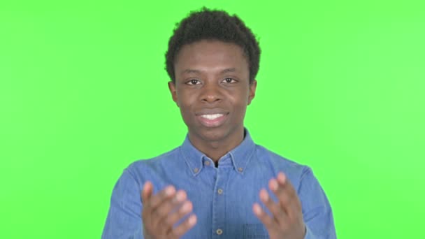 緑の背景に招待カジュアルアフリカ人男性を指す — ストック動画