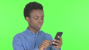 Casual African Man with Loss on Smartphone on Green Background