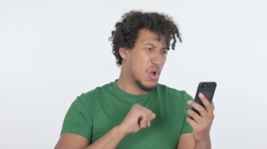 Casual African Man Celebrating Success on Smartphone on White Background