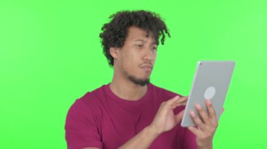 Casual African Man using Digital Tablet on Green Background