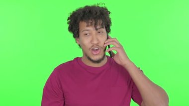 Aggressive Casual African Man Angry on Phone on Green Background