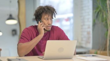Displeased Young African Man Talking Angrily on Smartphone at Work