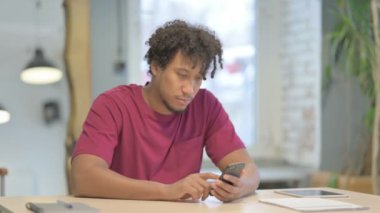 Young African Man Browsing Internet on Smartphone in Office