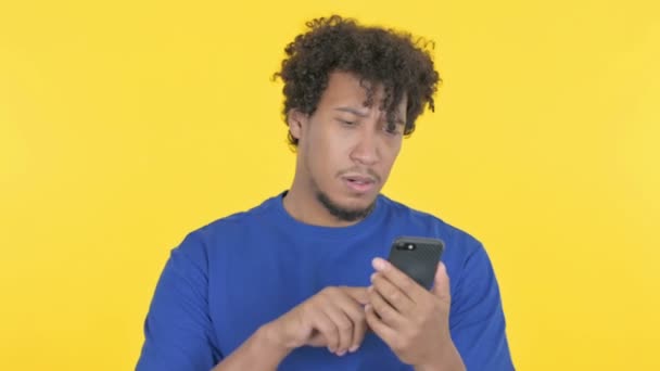 Casual African Man Browsing Smartphone Yellow Background — Stockvideo