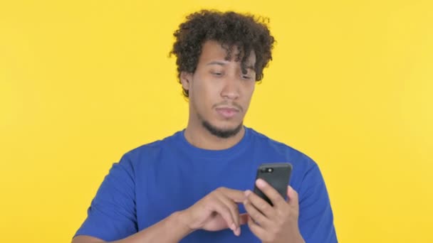 Casual African Man Celebrating Smartphone Yellow Background — Stock Video