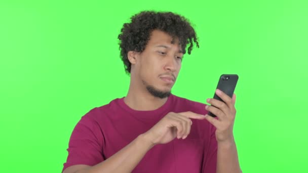 Casual African Man Browsing Smartphone Green Background — Vídeo de Stock