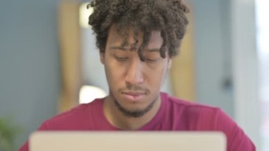 Close Up of Young African Man Shaking Head in Rejection while Working on Laptop