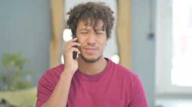 Upset Young African Man Talking on Phone in  Anger