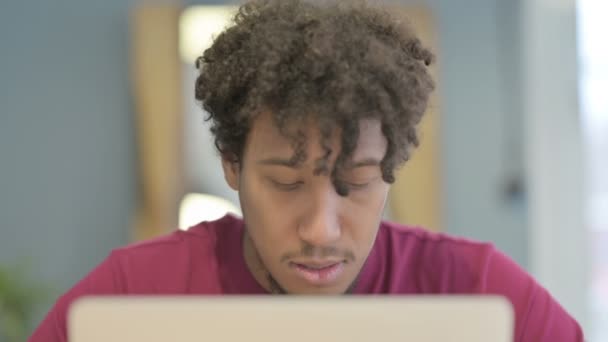 Close Young African Man Κοιτάζοντας Την Κάμερα Ενώ Χρησιμοποιείτε Laptop — Αρχείο Βίντεο