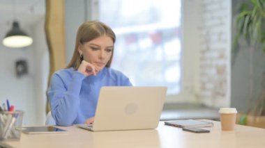 Dizüstü bilgisayarda çalışan dalgın genç kadın