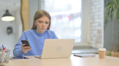 Laptop kullanırken Smartphone kullanan Genç Kadın