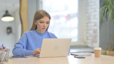 Dizüstü bilgisayar kullanırken Kameraya Gülümseyen Genç Kadın