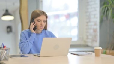 Laptop kullanırken Telefonda Konuşan Genç Kadın