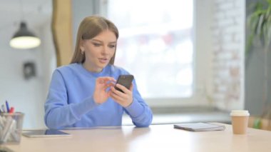 Successful Young Woman Celebrating Win on Smartphone