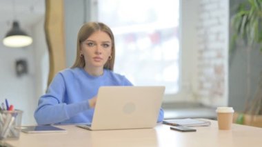 Shocked Young Woman Looking at Camera while using Laptop