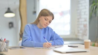 Pensive Young Woman Writing Letter in Office