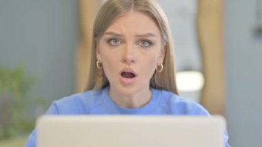 Close Up of Shocked Young Woman Looking at Camera while using Laptop