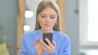 Excited Young Woman Celebrating Win on Smartphone