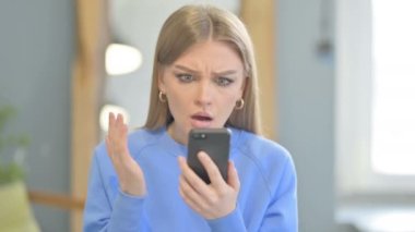 Shocked Young Woman Reacting to Loss on Smartphone