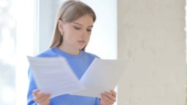Close Up of Young Woman Reading Documents while Sitting in Window