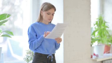 Upset Young Woman Feeling Sad after Reading Contract while Sitting in Window
