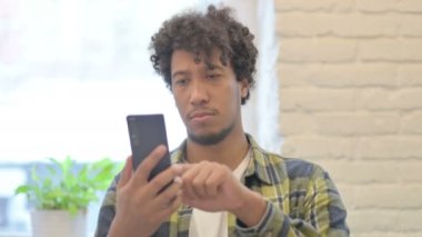 Young African Man using Smartphone for Browsing Internet