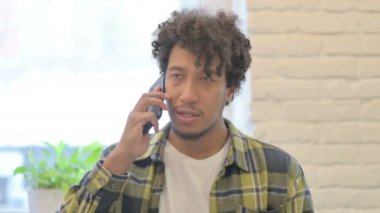 Young African Man Talking on Phone to Discuss Work