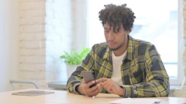 Happy Young African Man Celebrating Win on Smartphone