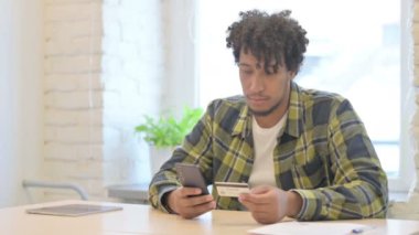 Young African Man Shopping Online by Using Smartphone