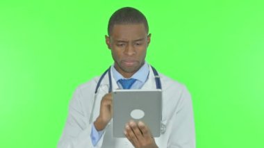 Young African Doctor using Digital Tablet on Green Background