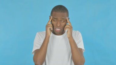 Young African Man with Migraine on Blue Background