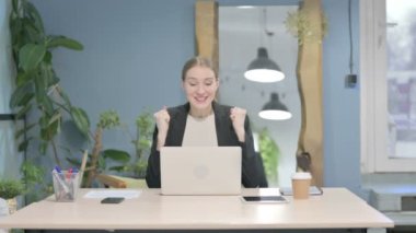 Young Businesswoman Celebrating Online Success on Laptop in Office