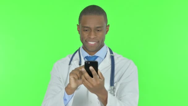 Young African Doctor Using Smartphone Green Background — Stockvideo