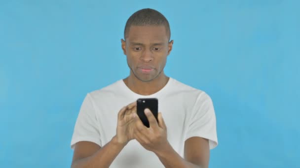 非洲年轻人在蓝色背景下浏览智能手机 — 图库视频影像