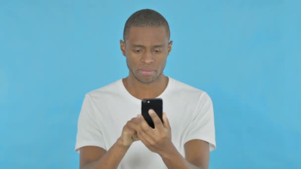 Νεαρός Αφρικανικός Άνθρωπος Απώλεια Για Smartphone Μπλε Φόντο — Αρχείο Βίντεο