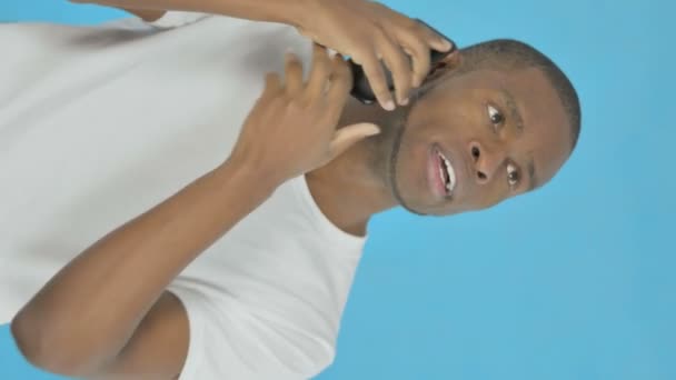 Вертикальное Видео Молодой Афроамериканец Разговаривает Телефону Голубом Фоне — стоковое видео